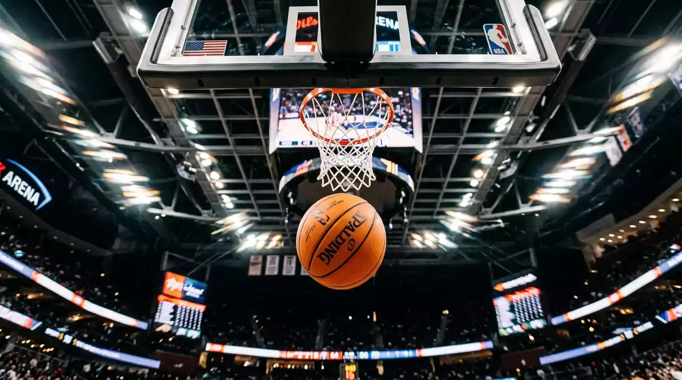 Basketball in mid-flight approaching the hoop and net shot from below with bright arena lights above